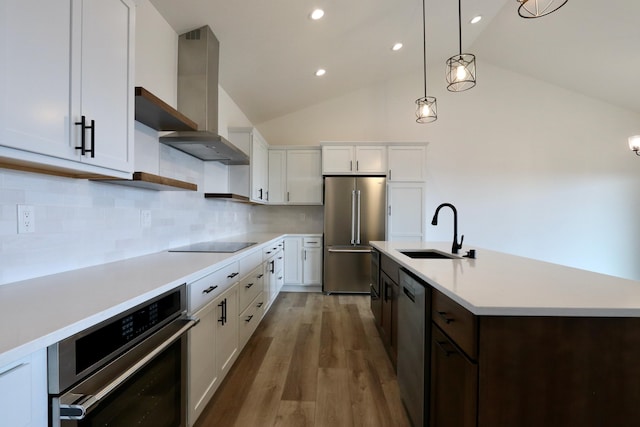 kitchen with wall chimney exhaust hood, decorative backsplash, appliances with stainless steel finishes, and hardwood / wood-style floors