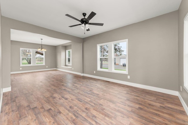 unfurnished living room featuring ceiling fan with notable chandelier and hardwood / wood-style floors