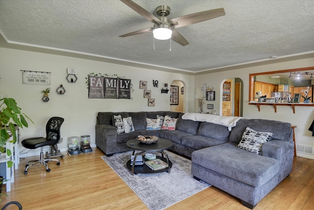 living room with ceiling fan, a textured ceiling, and wood-type flooring