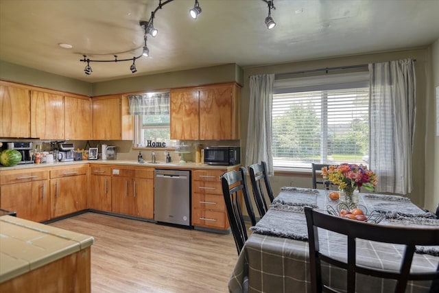 kitchen featuring sink, rail lighting, light hardwood / wood-style flooring, stainless steel dishwasher, and tile countertops