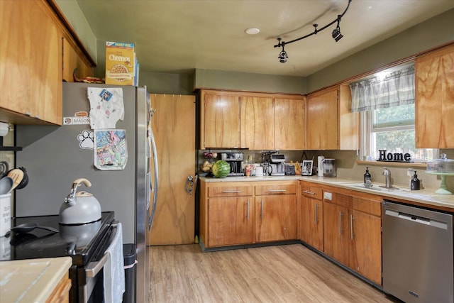 kitchen featuring sink, light wood-type flooring, track lighting, and appliances with stainless steel finishes