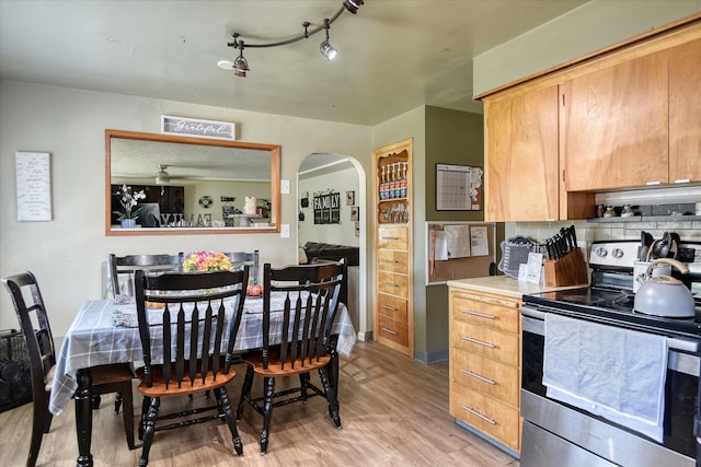 kitchen with stainless steel range with electric stovetop, tasteful backsplash, track lighting, and light hardwood / wood-style flooring