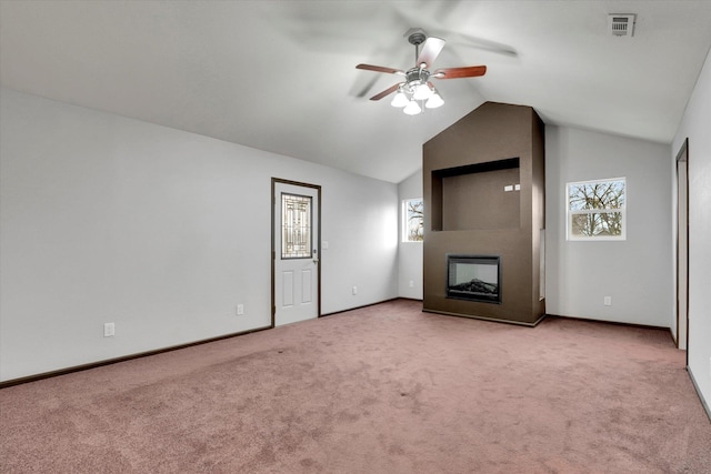 unfurnished living room featuring light carpet, a large fireplace, vaulted ceiling, and plenty of natural light