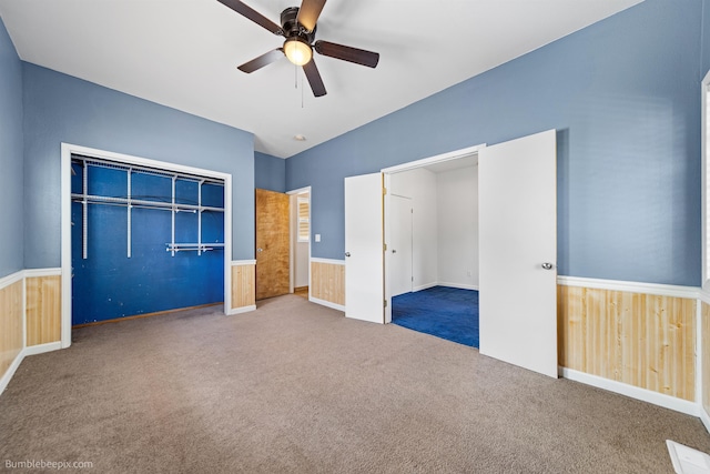 unfurnished bedroom featuring ceiling fan, wood walls, and a closet