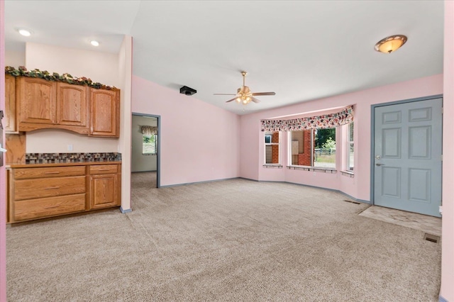 unfurnished living room with vaulted ceiling, ceiling fan, and light colored carpet