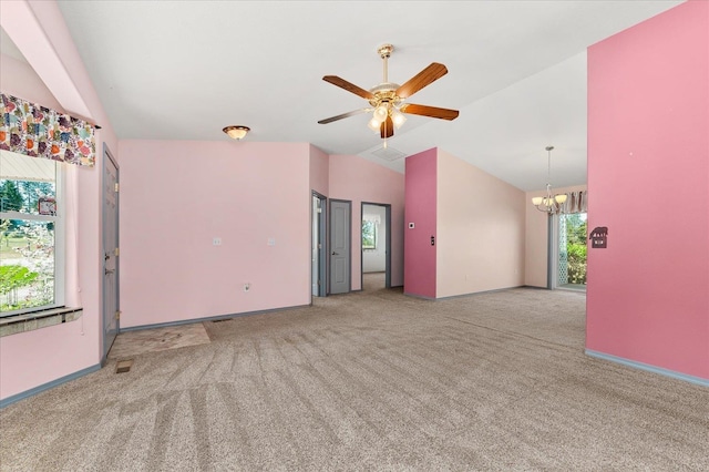 carpeted empty room with lofted ceiling and ceiling fan with notable chandelier