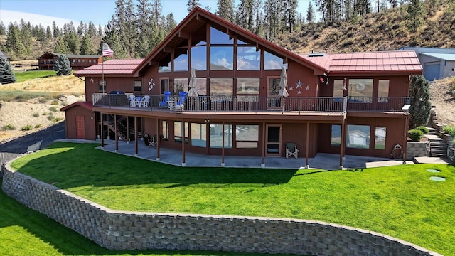 rear view of house with a lawn, a wooden deck, and a patio area