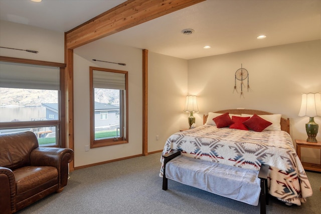 bedroom with multiple windows, beamed ceiling, and carpet