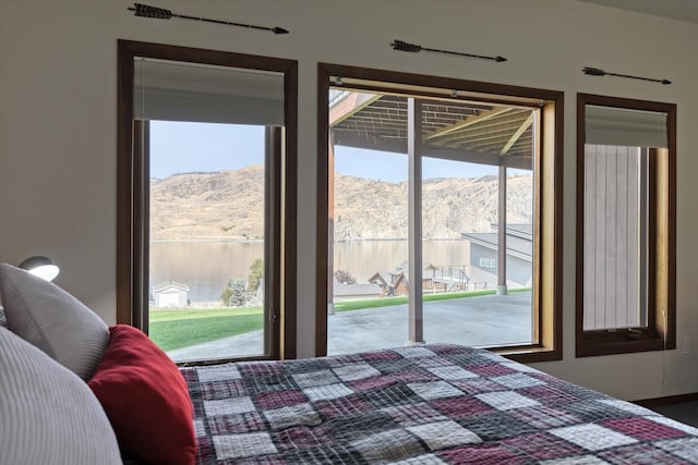 bedroom with a water and mountain view and access to exterior