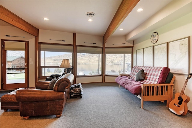 carpeted living room with beamed ceiling