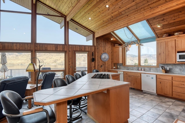 kitchen with a mountain view, white appliances, wooden ceiling, tile counters, and vaulted ceiling with beams