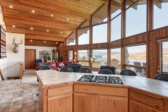 kitchen with wood ceiling, high vaulted ceiling, stainless steel gas stovetop, and tile countertops