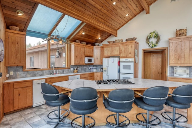 kitchen featuring wooden ceiling, white appliances, a skylight, and sink