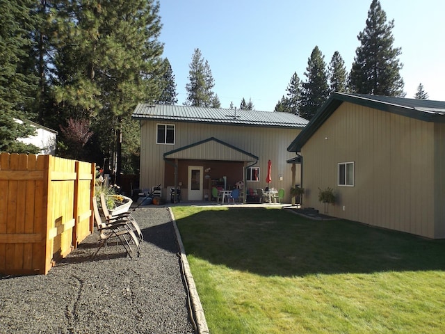 back of property featuring a yard, fence, metal roof, and a patio area