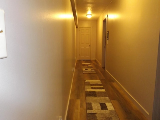 corridor featuring baseboards and dark wood-style flooring