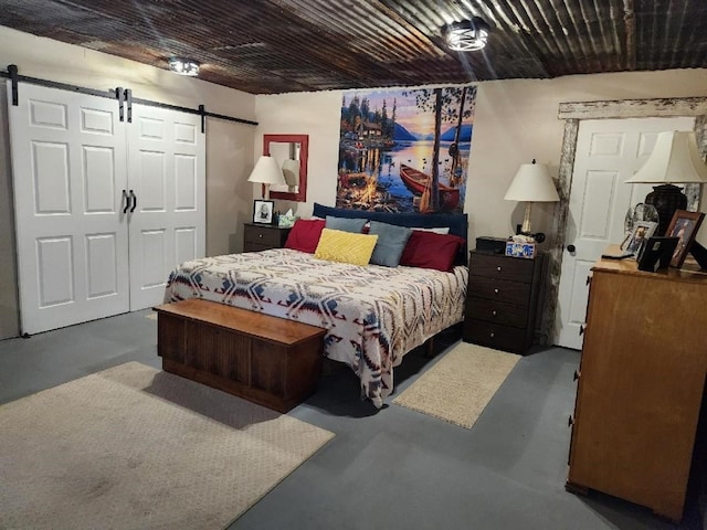 bedroom with a barn door and finished concrete floors