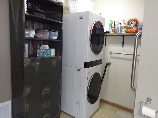 clothes washing area featuring baseboards, laundry area, stacked washer and dryer, and visible vents