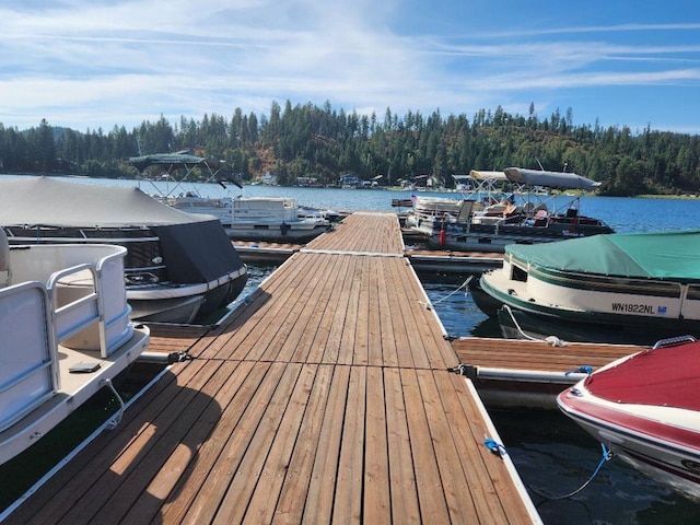 view of dock with a forest view and a water view