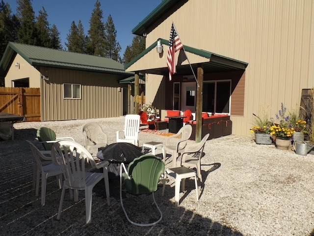 rear view of house with fence, metal roof, an outdoor fire pit, and a patio area