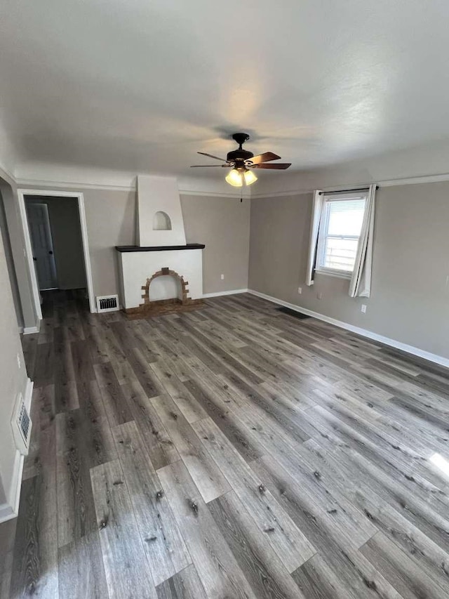 unfurnished living room featuring a large fireplace, ceiling fan, and hardwood / wood-style flooring