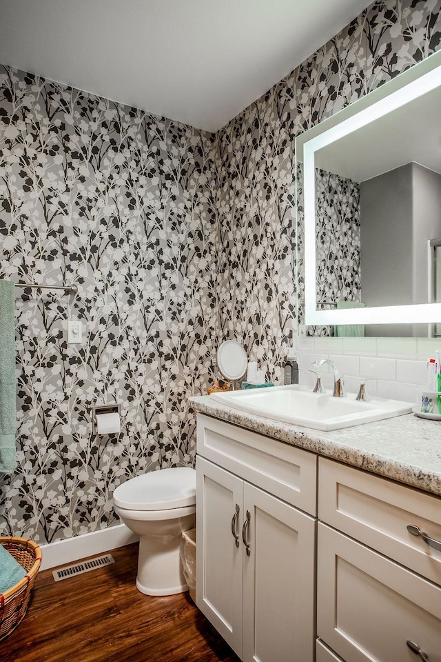 bathroom featuring hardwood / wood-style floors, backsplash, toilet, and vanity