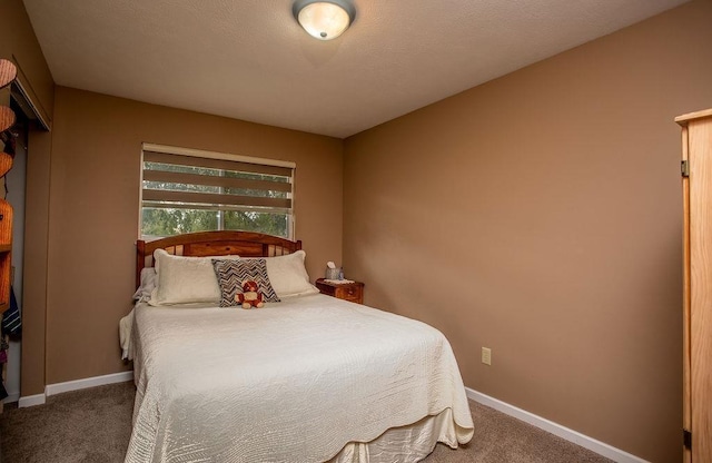 bedroom with dark colored carpet and baseboards