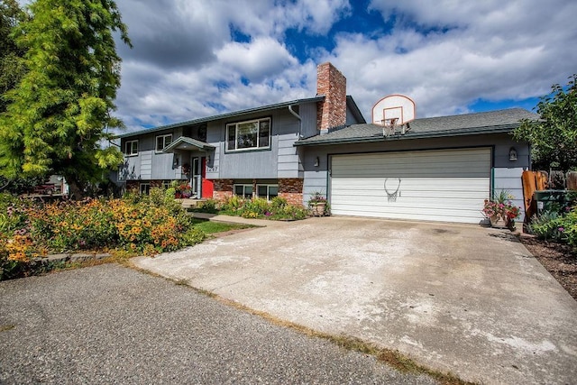 bi-level home with a garage, concrete driveway, brick siding, and a chimney