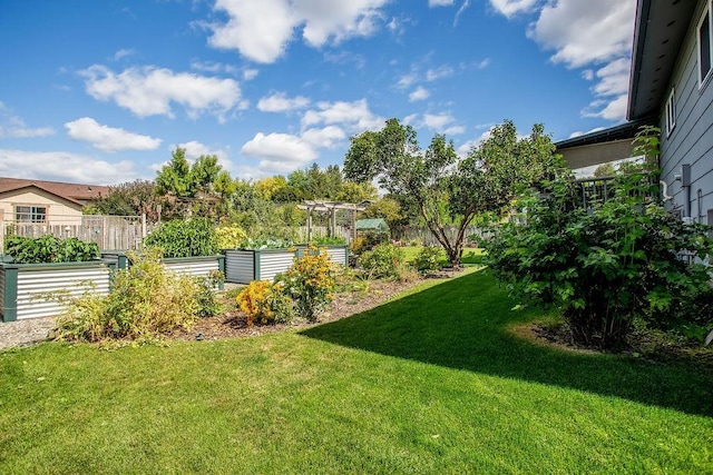 view of yard featuring fence, a garden, and a pergola