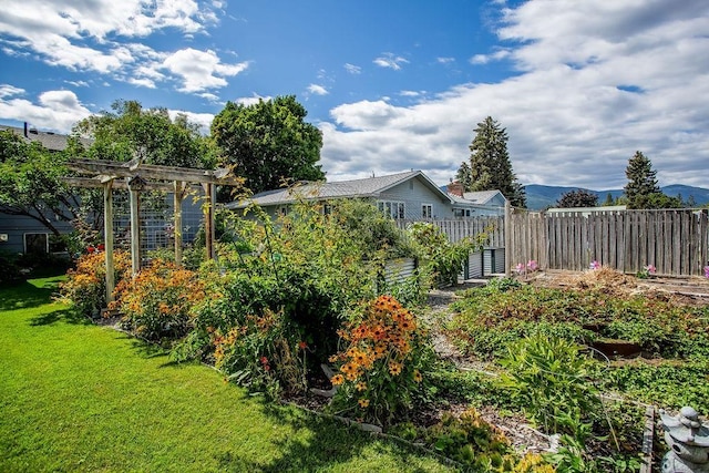 view of yard featuring a garden, fence, and a mountain view