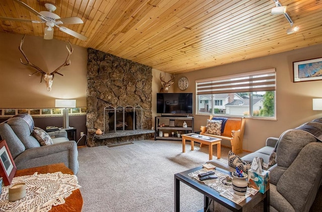 carpeted living room featuring lofted ceiling, a ceiling fan, wood ceiling, a stone fireplace, and track lighting