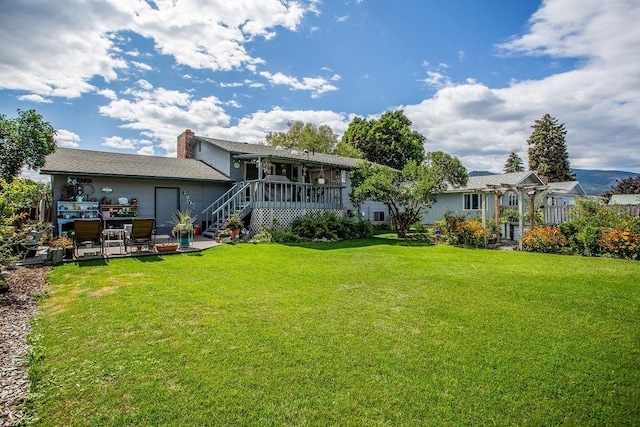 back of property featuring stairs, a lawn, and a wooden deck