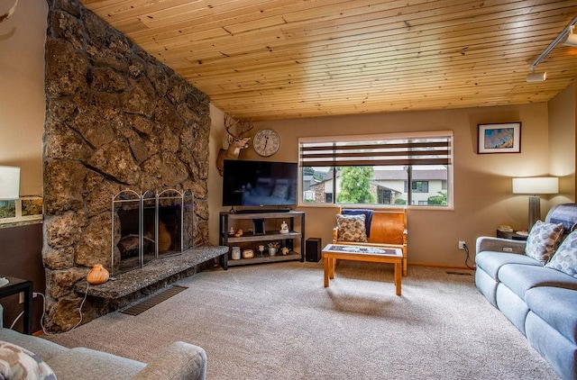 carpeted living room featuring lofted ceiling, wood ceiling, track lighting, and a stone fireplace