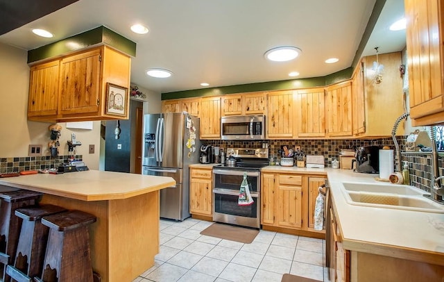 kitchen featuring appliances with stainless steel finishes, light tile patterned floors, backsplash, and kitchen peninsula