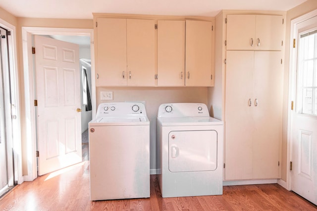 clothes washing area featuring light wood-type flooring, cabinets, and washer and clothes dryer