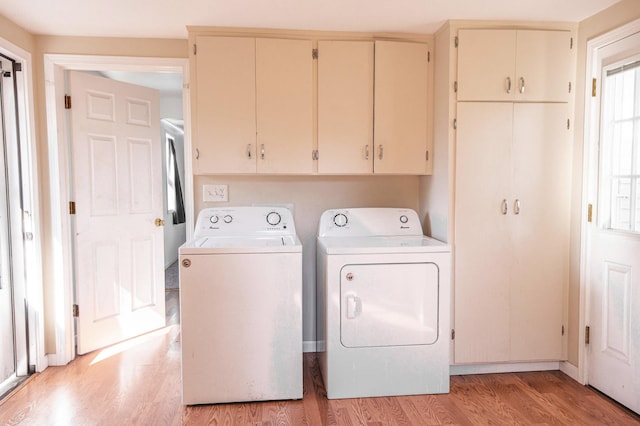 laundry room with light wood-style floors, separate washer and dryer, and cabinet space