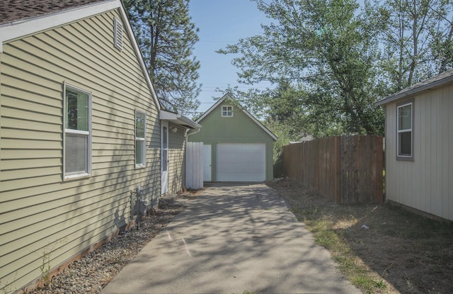 exterior space featuring driveway, an outdoor structure, fence, and a detached garage