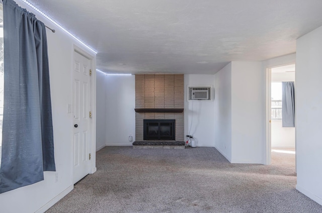 unfurnished living room with a wall mounted AC, carpet floors, and a brick fireplace