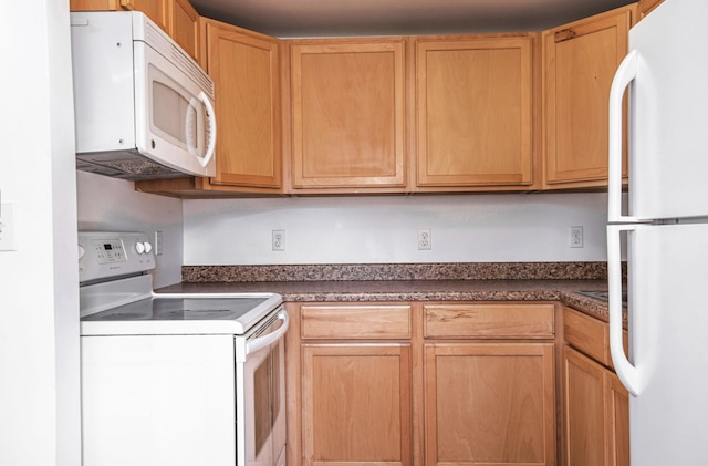 kitchen featuring white appliances and dark countertops