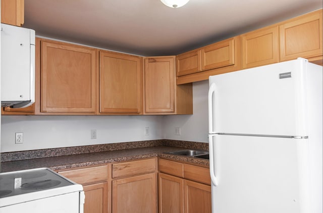 kitchen with water heater, white appliances, dark countertops, and a sink