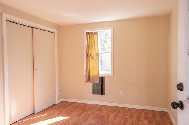 unfurnished bedroom with a closet, visible vents, baseboards, and wood finished floors