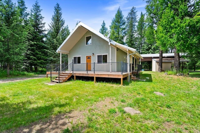 rear view of house with a lawn, a wooden deck, and a shed