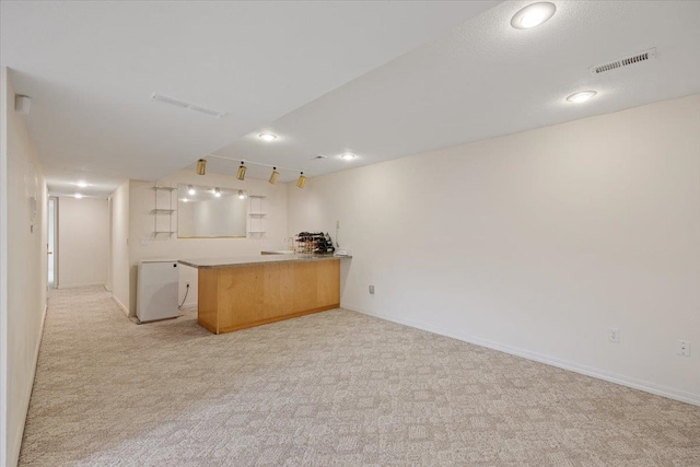 kitchen with light brown cabinetry, rail lighting, light carpet, and kitchen peninsula