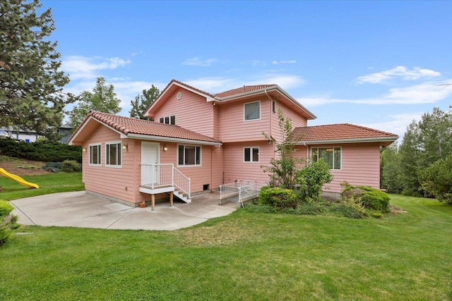 back of property with a lawn and a patio