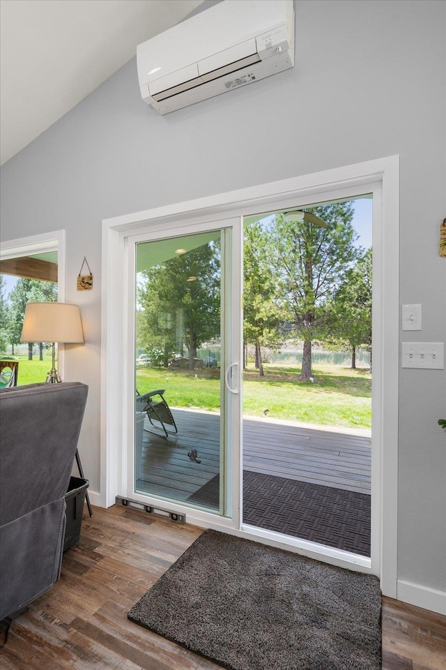 doorway to outside with lofted ceiling, an AC wall unit, baseboards, and wood finished floors