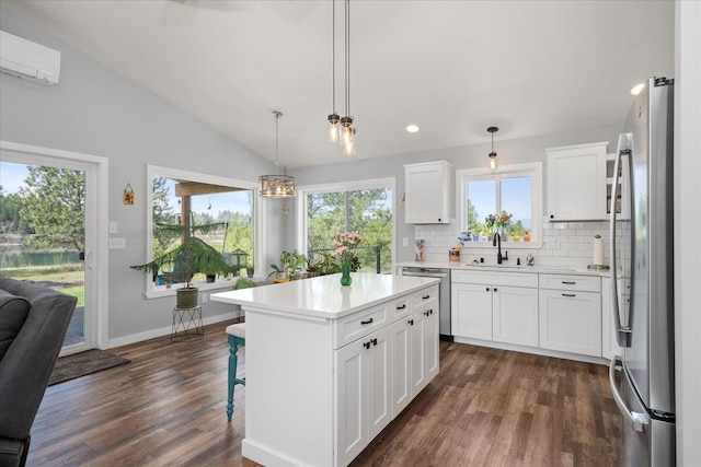 kitchen with lofted ceiling, a wall unit AC, stainless steel appliances, a sink, and light countertops