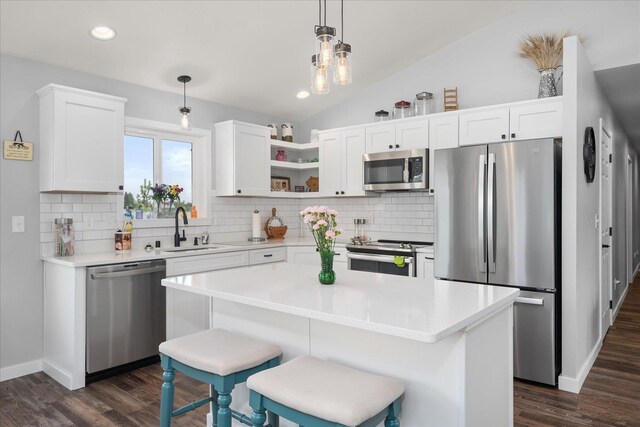 kitchen with dark wood finished floors, stainless steel appliances, white cabinetry, vaulted ceiling, and a sink