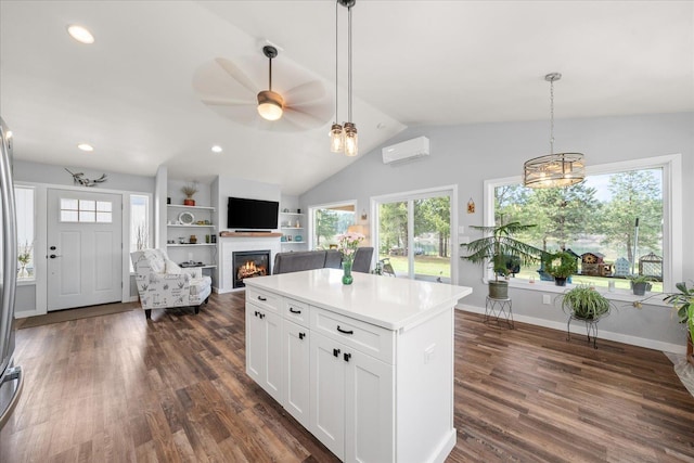 kitchen with lofted ceiling, a warm lit fireplace, white cabinetry, dark wood-style floors, and a wall mounted air conditioner