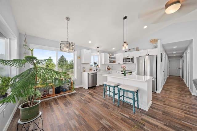 kitchen with lofted ceiling, stainless steel appliances, light countertops, white cabinetry, and backsplash