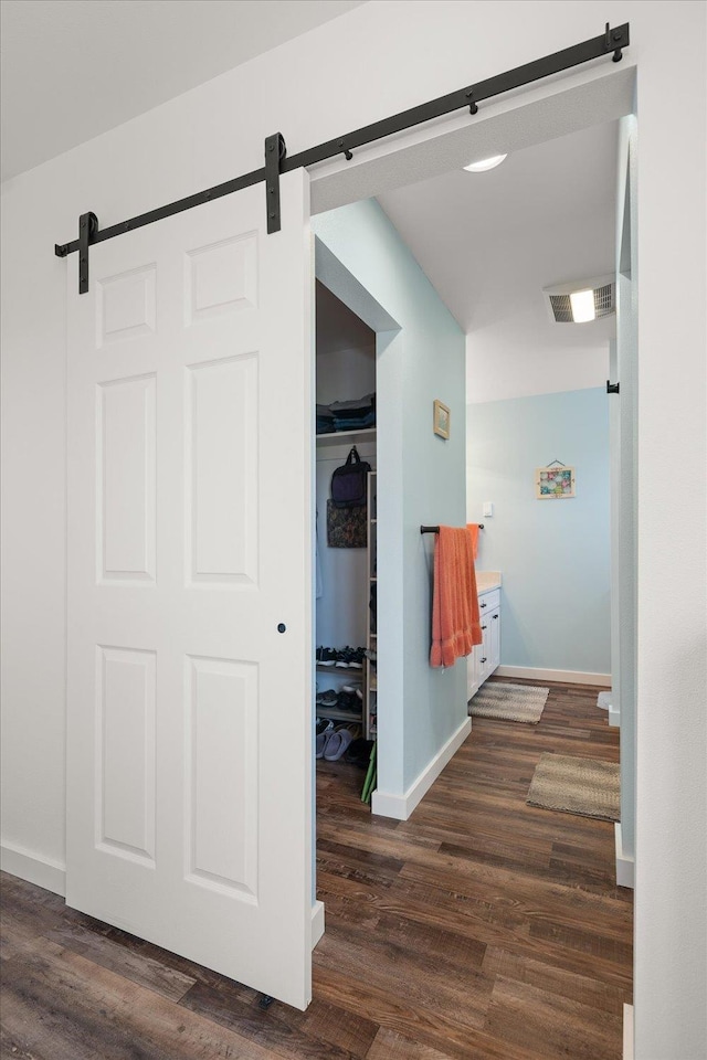 hallway featuring dark wood-style floors, a barn door, and visible vents