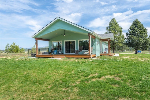 rear view of property featuring a lawn, a deck, and a ceiling fan